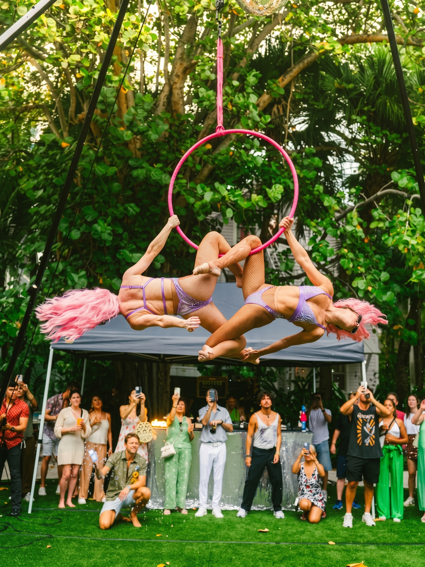 Aerialists in pink wigs performing on the hoop above the Season 1 crowd